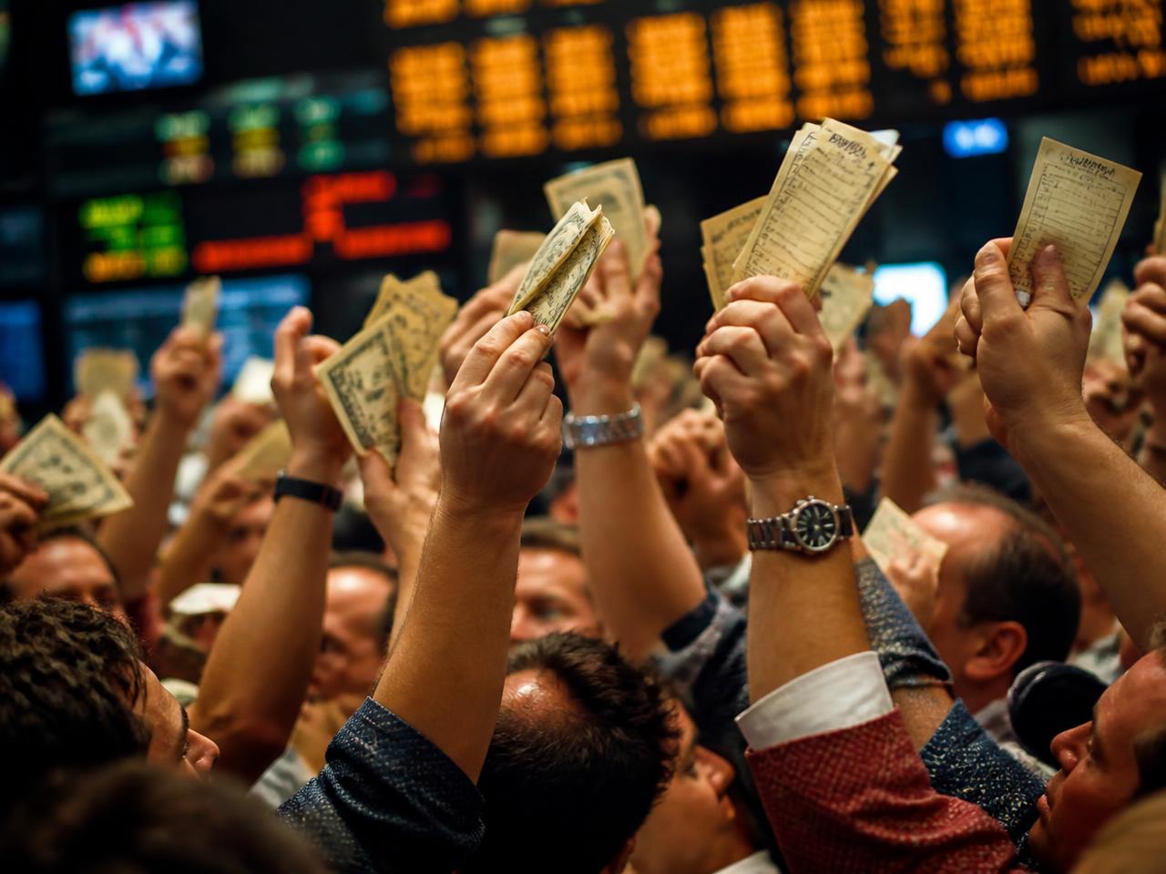 Multitud de manos levantadas con billetes y órdenes en el piso de la bolsa